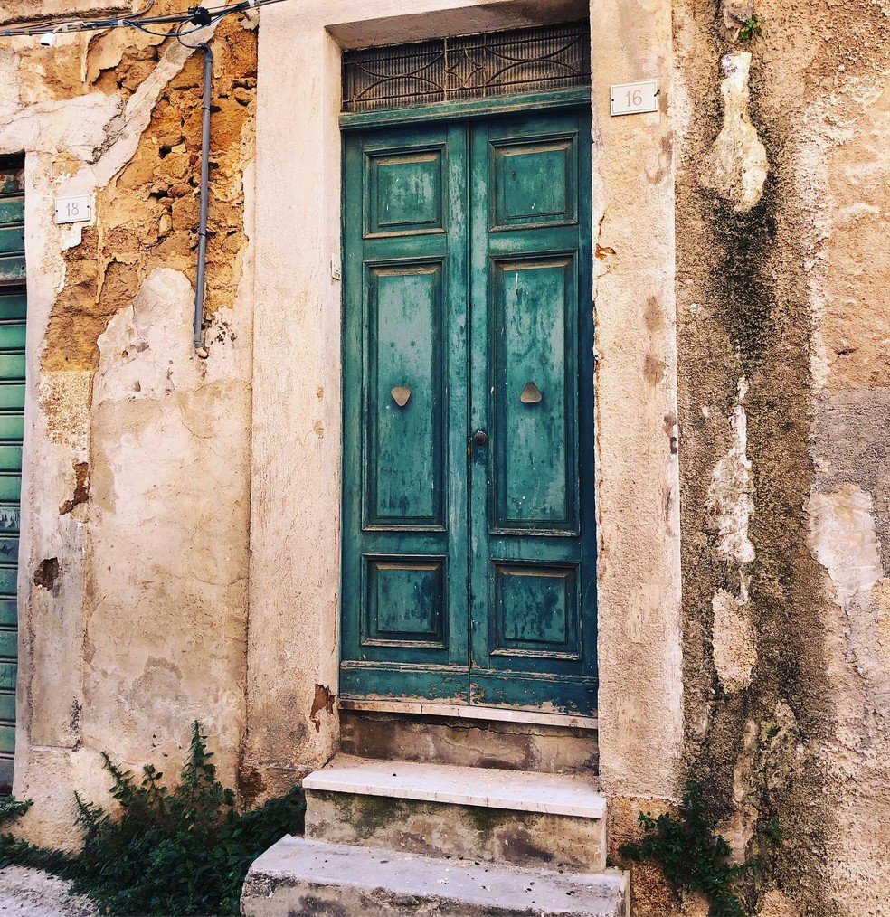 A entrada de uma das casas possui uma porta dupla verde — Foto: Instagram / @sicilydreamhome / Reprodução