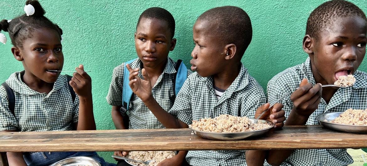 As crianças no Haiti comem uma refeição fornecida como parte do programa de alimentação escolar do PMA As crianças no Haiti comem uma refeição fornecida como parte do programa de alimentação escolar do PMA