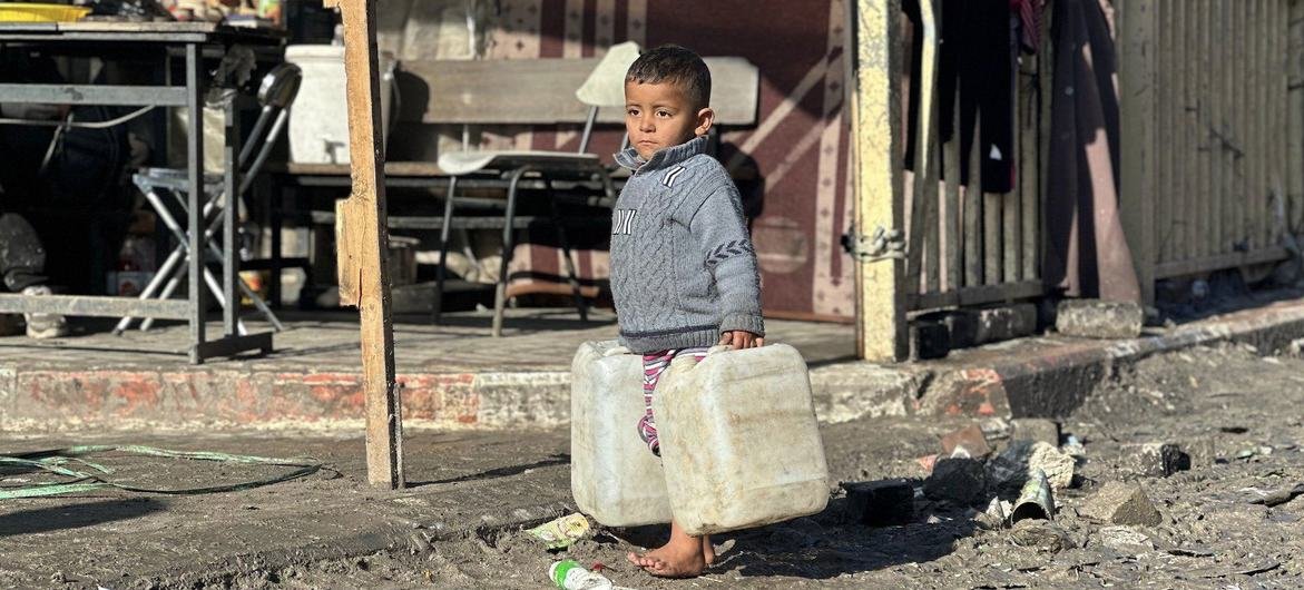 Um menino carrega latas de água na Faixa de Gaza Um menino carrega latas de água na Faixa de Gaza