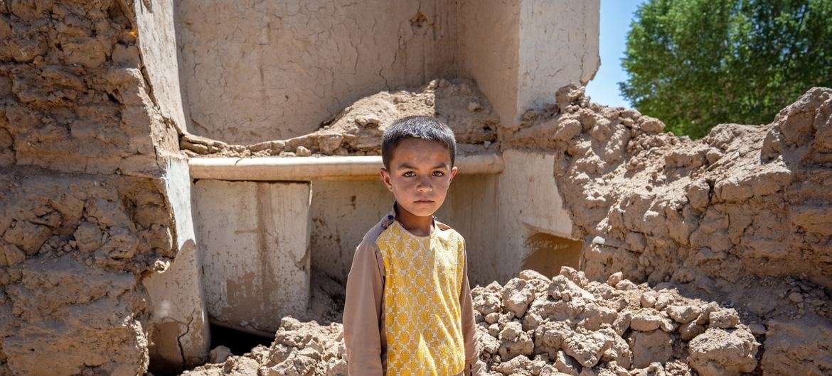 Farzan, de 9 anos, nas ruínas de sua casa na província de Ghor, oeste do Afeganistão, em maio de 2024